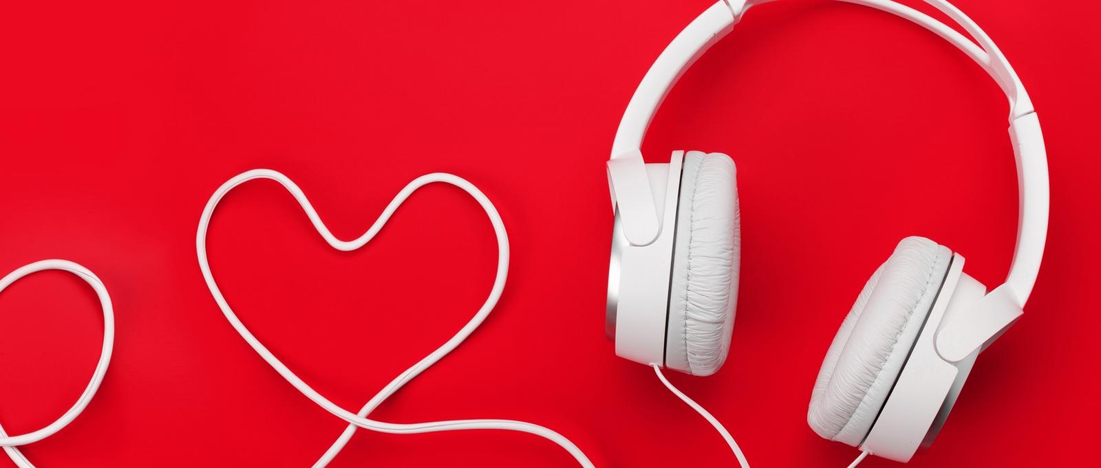 White headphones on bright red background with cable arranged in heart shape, symbolising CPR.