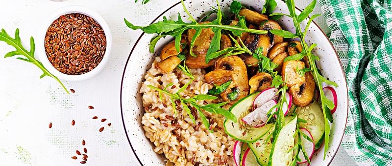 Breakfast oatmeal porridge with green herbs on mushrooms, cucumber, radish and flax seeds.