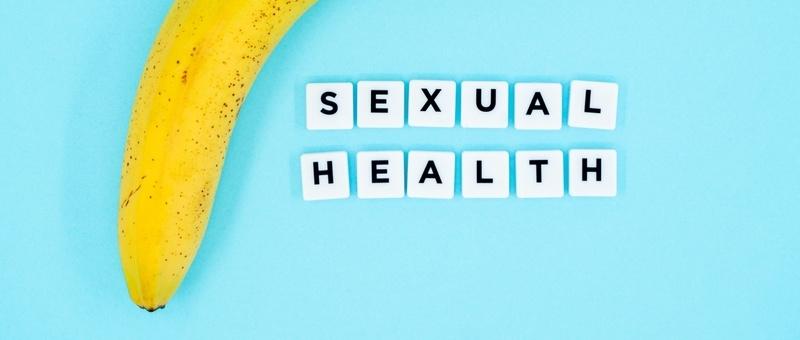 Type led - SEXUAL HEALTH printed on white blocks beside banana against blue background.