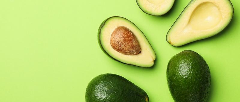 Whole and sliced avodacos against a green background.