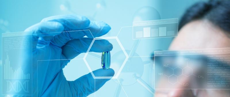 Hand in blue glove holding a capsule with digital scientific overlays showing chemical formulas and data graphs.