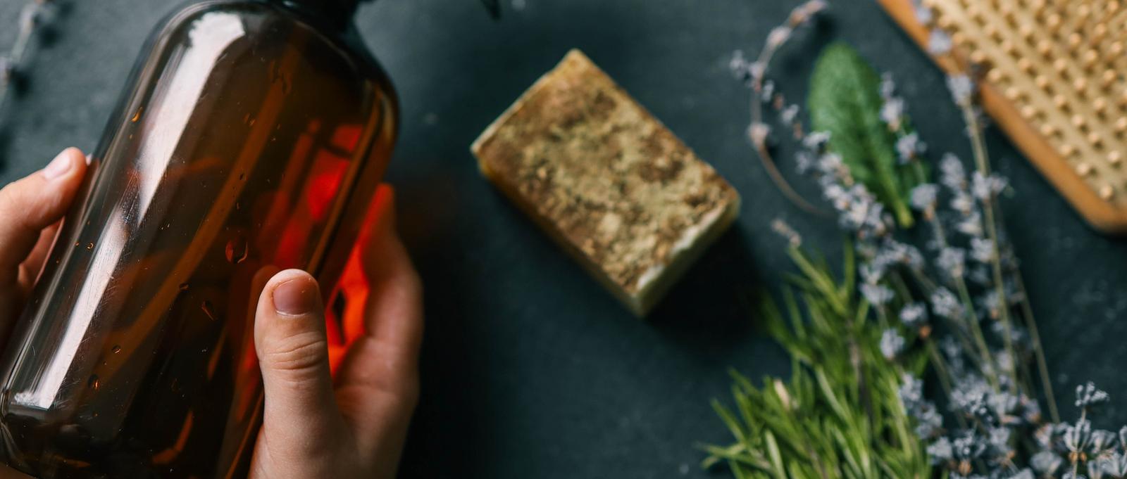 Natural spray for hair growth with herbs in hands.