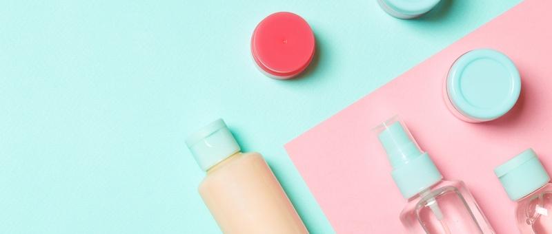 Assorted toiletries against a pink and blue background.