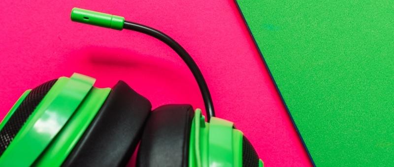 Gaming headset with mic against pink and green background.