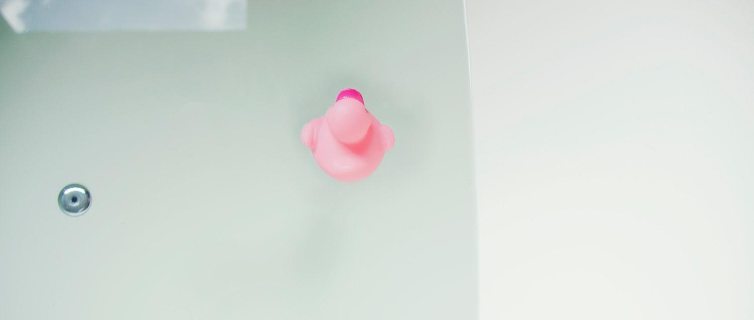 Photo of a pink rubber duck in a bathtub.
